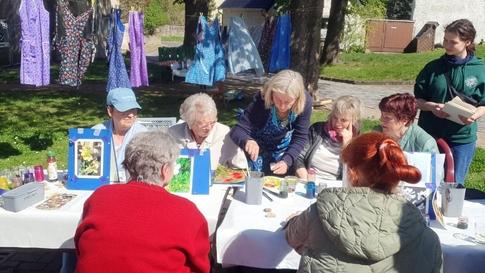 Menschen sitzen im Freien an einem gedeckten Tisch hinter dem Kunstkonsum Heiligenthal.