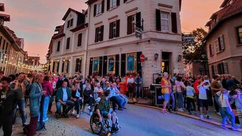 Kultur- und Begegnungsstätte Hamburger Tor: vor einem Gebäude stehen abends bei untergehender Sonne auf einem Straßenfest viele Leute auf der Straße.